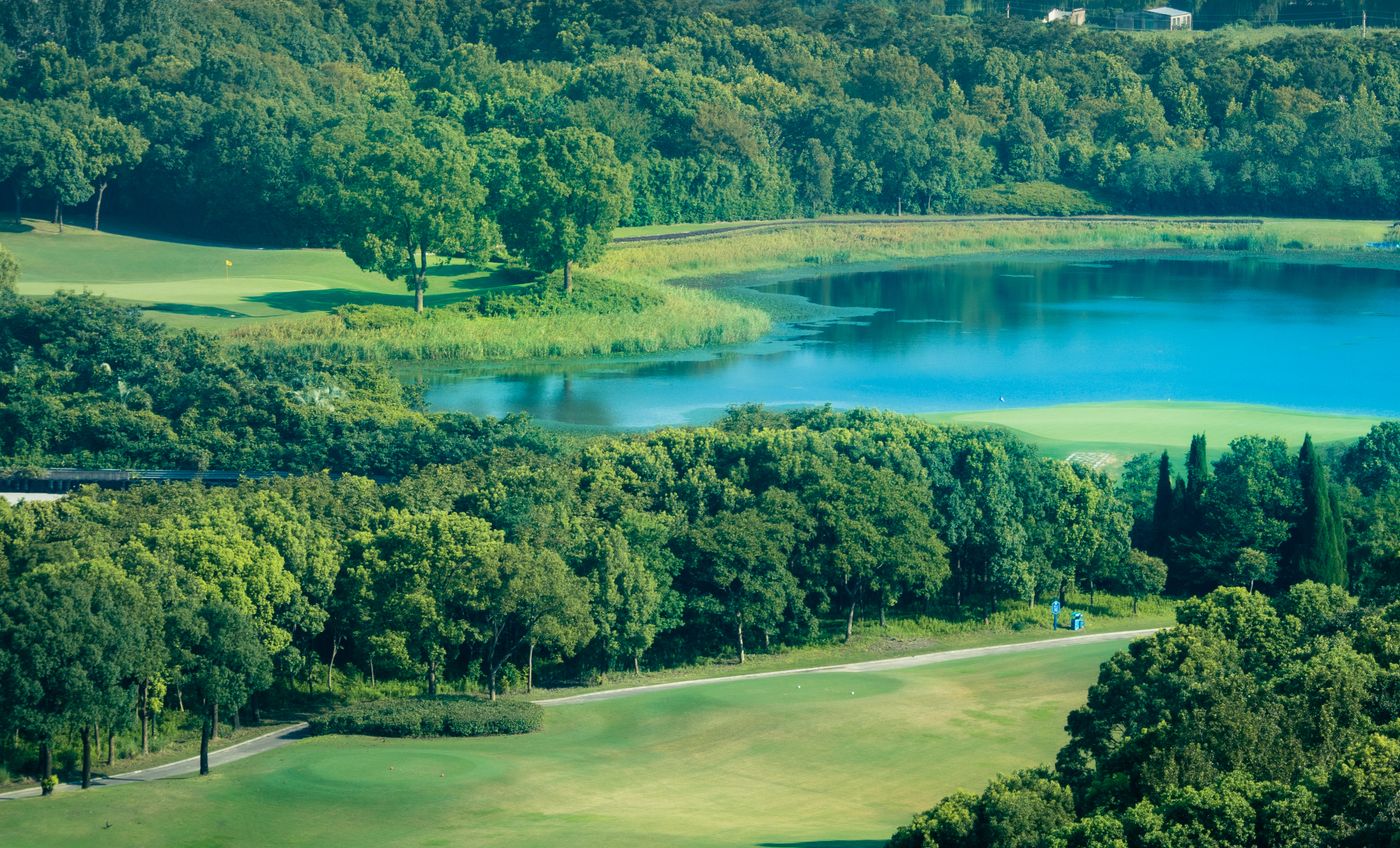 A golf course seen from the air, a lake at its centre